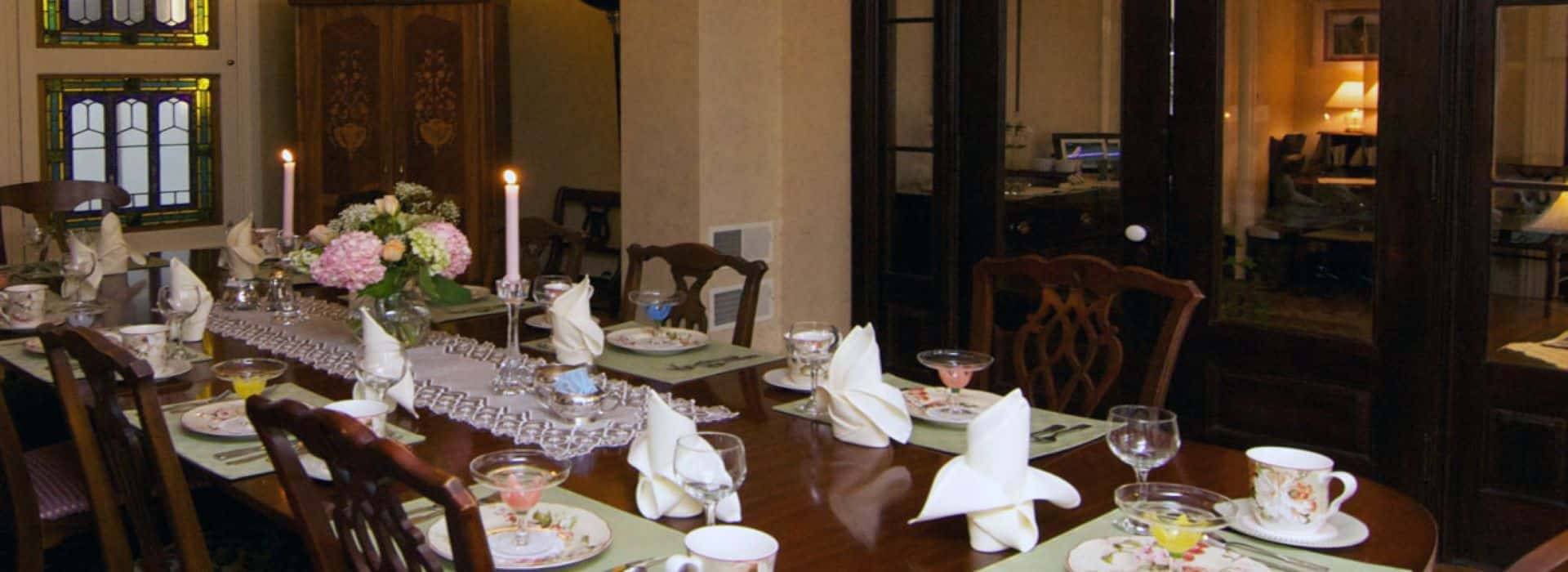 Large dining table set for eight with vase of flowers and lit candles